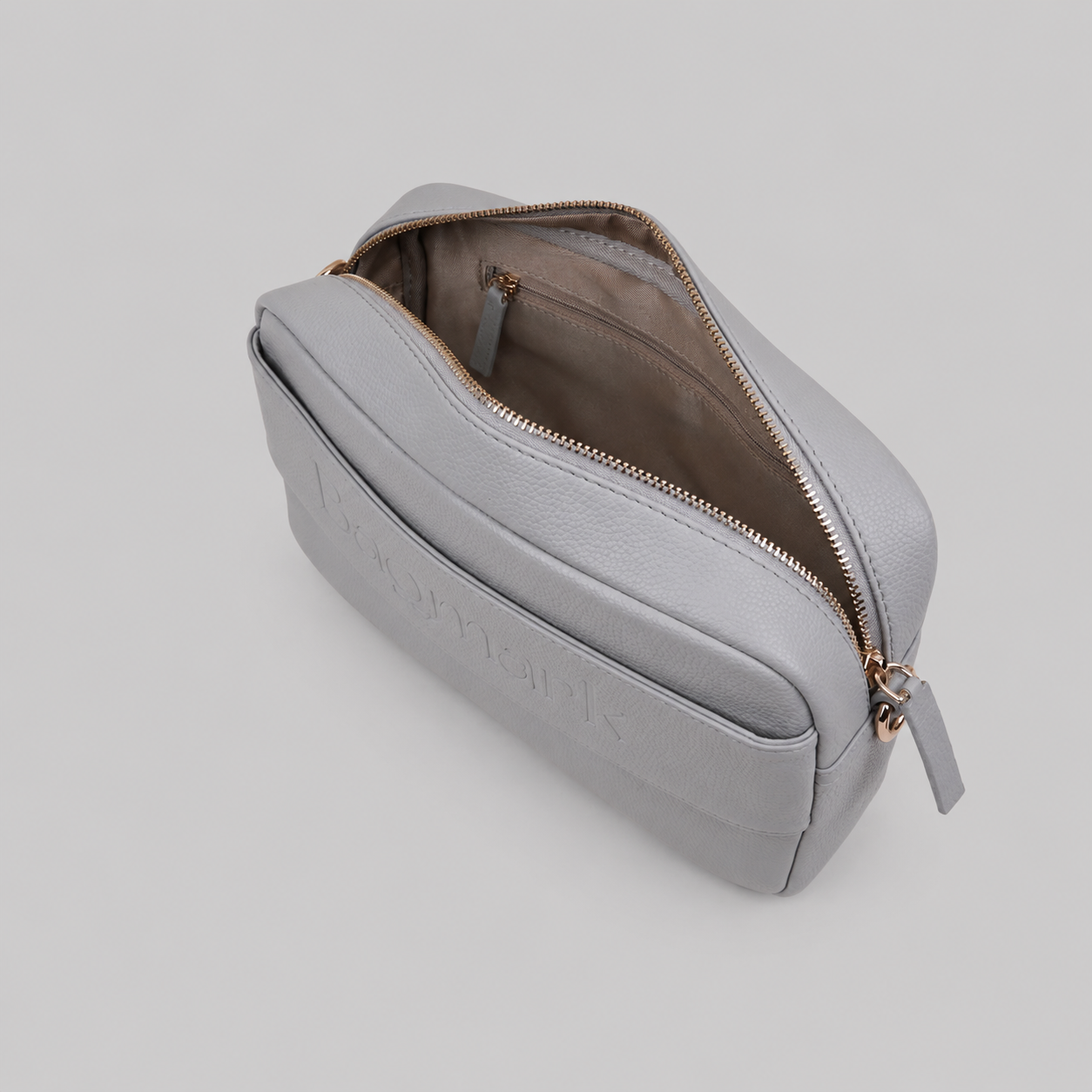 The Daily in Stone bookmark-inspired crossbody bag with gold zipper displaying inner compartments of the bag